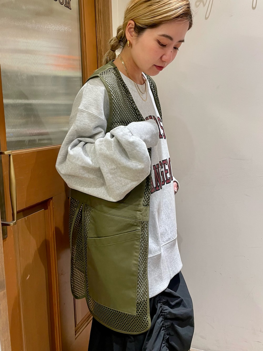 グレー系のスウェット、グリーン系のベスト、ブラック系のスカートを着用したレディースの秋コーディネートの4枚目の写真