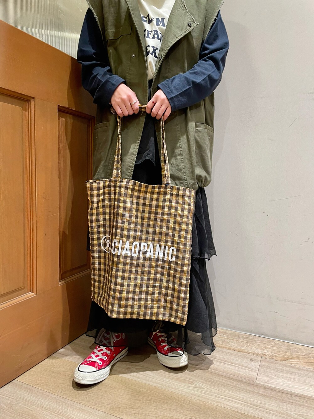 グリーン系のベスト、ブルー系のTシャツ/カットソー、ブラック系のスカートを着用したレディースの秋コーディネートの5枚目の写真