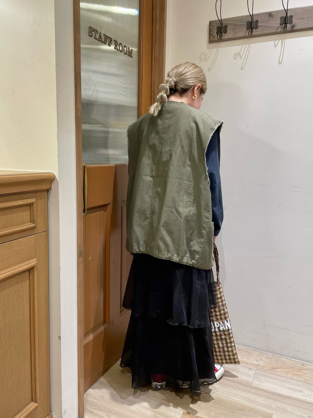 グリーン系のベスト、ブルー系のTシャツ/カットソー、ブラック系のスカートを着用したレディースの秋コーディネートの2枚目の写真