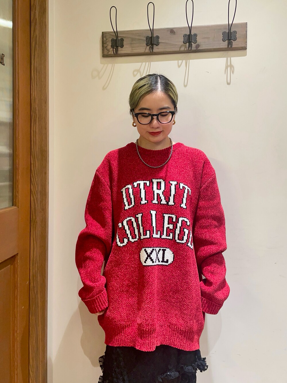 レッド系のニット/セーター、ブラック系のスカート、ブラウン系のハンドバッグを着用したレディースの秋コーディネートの3枚目の写真