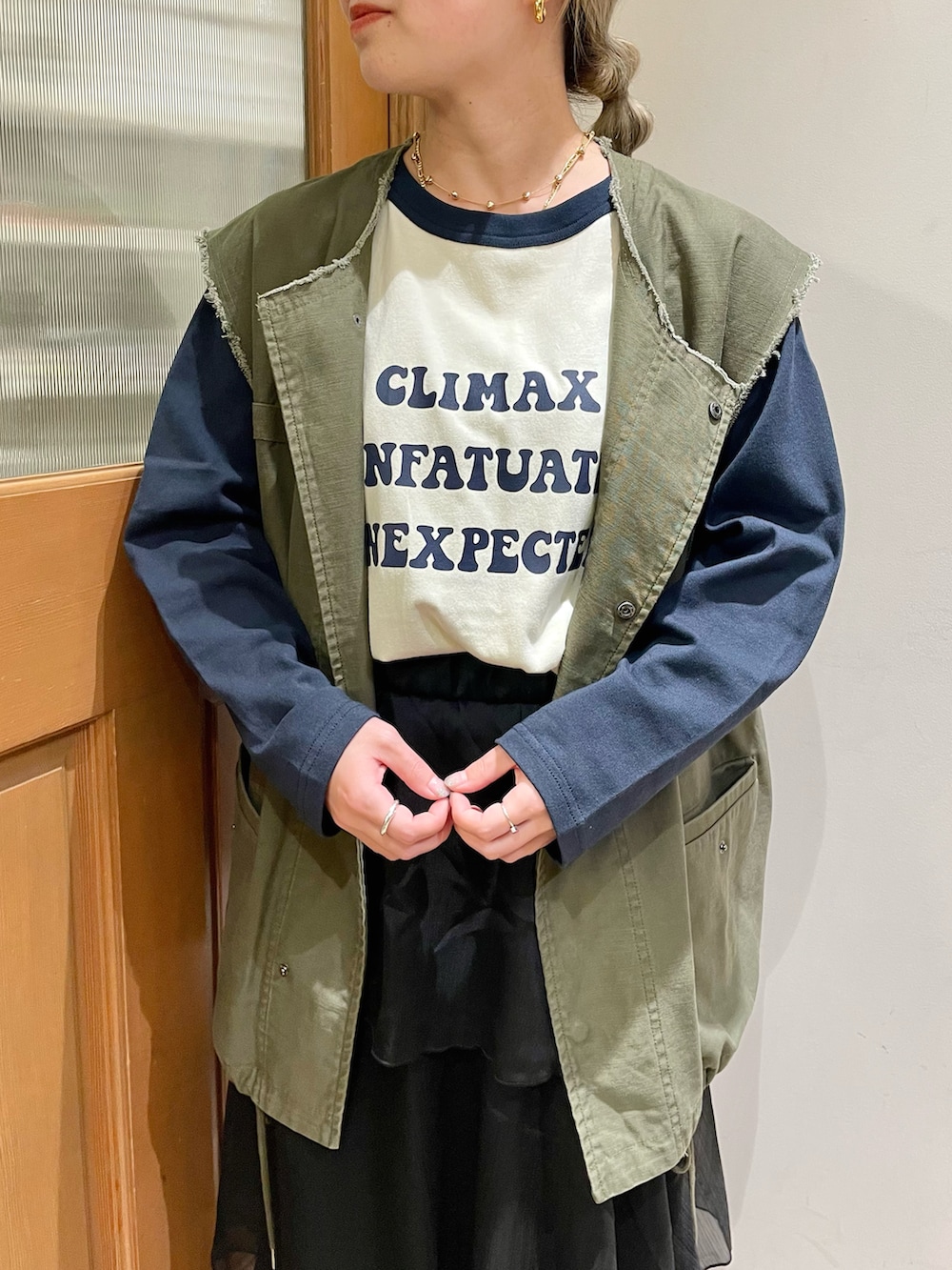 グリーン系のベスト、ブルー系のTシャツ/カットソー、ブラック系のスカートを着用したレディースの秋コーディネートの3枚目の写真