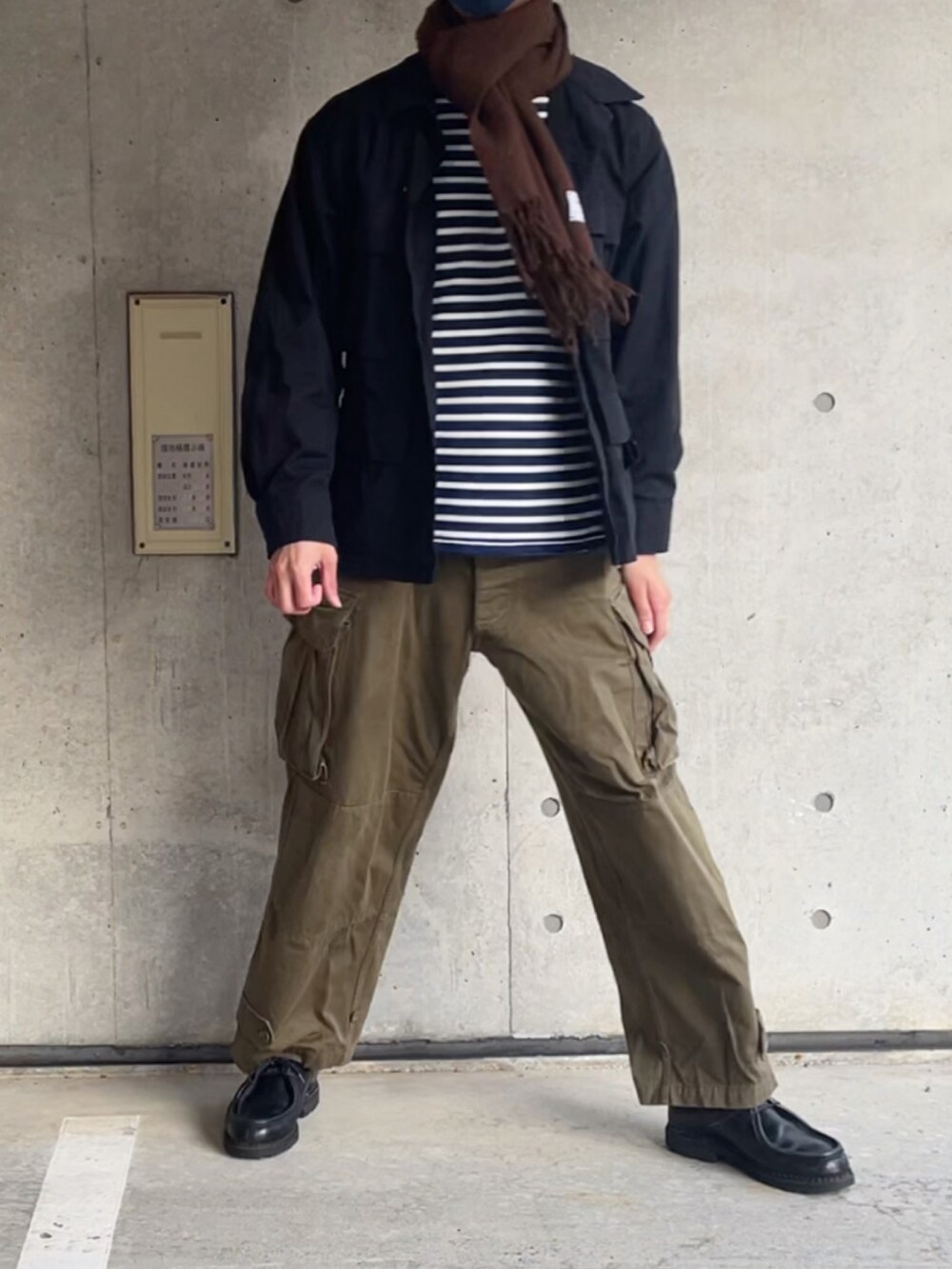 ブラック系のミリタリージャケット、ホワイト系のTシャツ/カットソー、グリーン系のカーゴパンツを着用したメンズの冬コーディネートの2枚目の写真