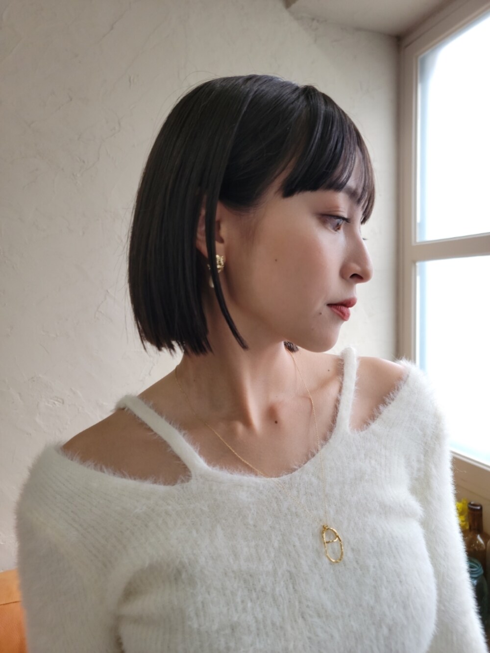 ホワイト系のニット/セーター、ブラック系のデニムパンツ、ゴールド系のピアス（両耳用）を着用したレディースの秋コーディネートの2枚目の写真