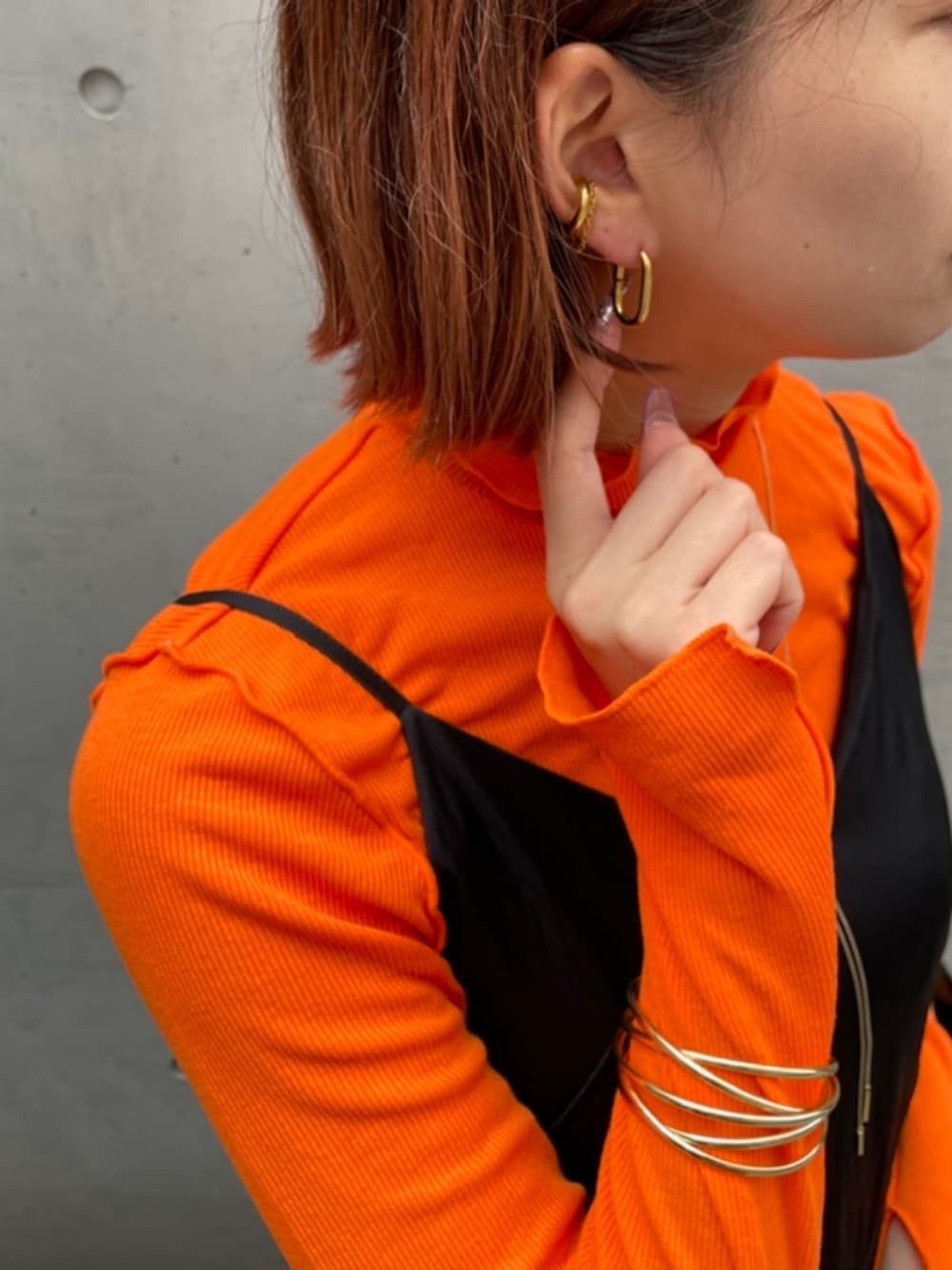 ブラック系のワンピース、オレンジ系のTシャツ/カットソー、ブラック系のハンドバッグを着用したレディースの秋コーディネートの2枚目の写真