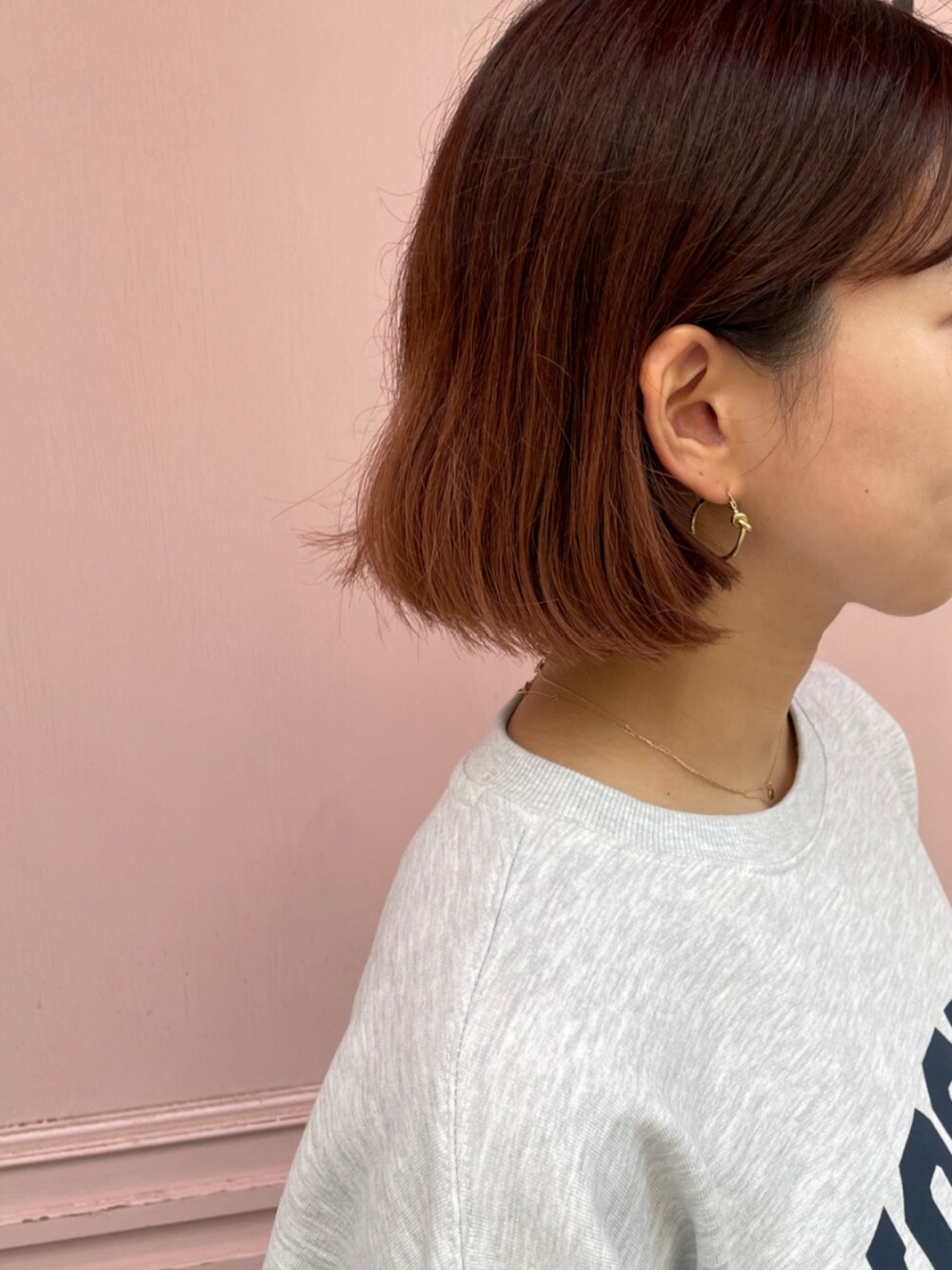 グレー系のスウェット、ゴールド系のネックレス、ゴールド系のピアス（両耳用）を着用したレディースの秋コーディネートの2枚目の写真