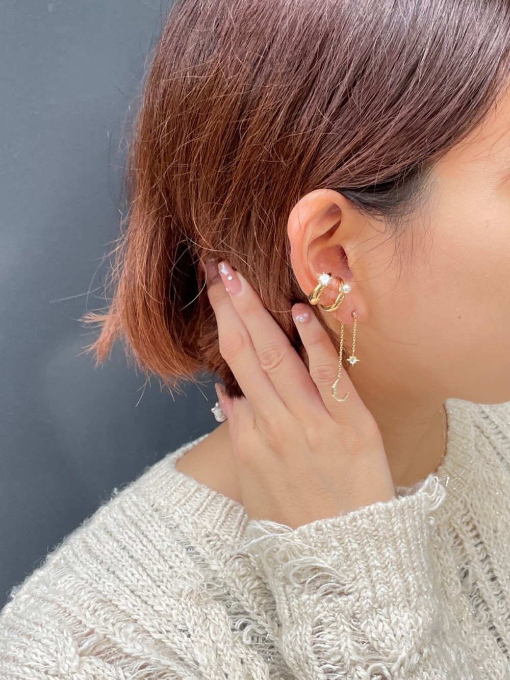 ベージュ系のニット/セーター、ゴールド系のピアス（両耳用）、ゴールド系のイヤーカフを着用したレディースの秋コーディネートの2枚目の写真
