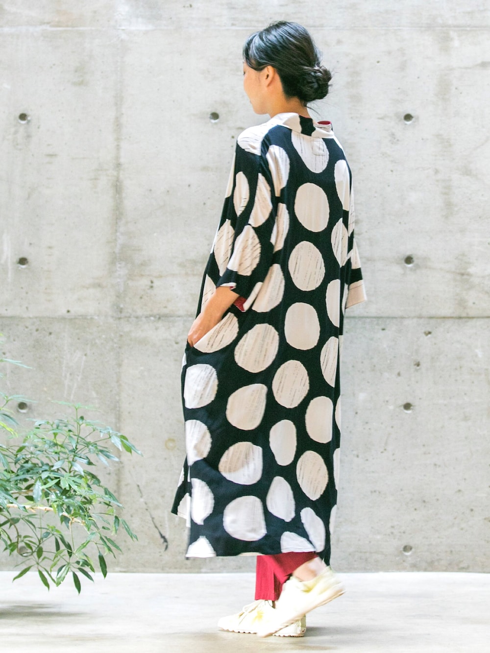 ブラック系のワンピース、レッド系のパンツ、ホワイト系のスニーカーを着用したレディースの春コーディネートの2枚目の写真