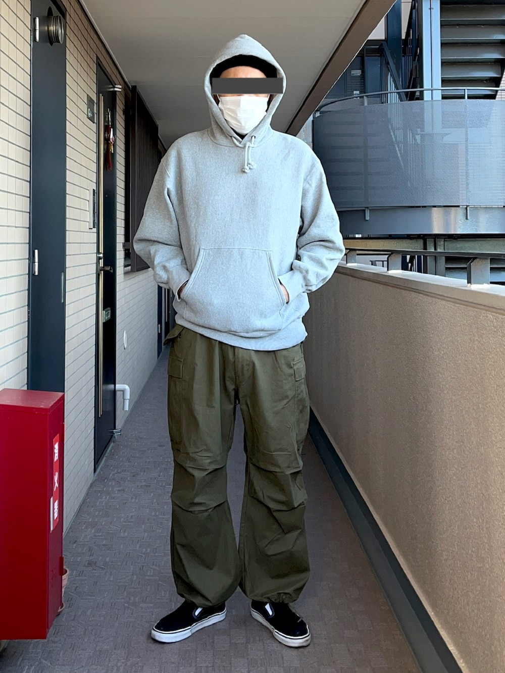 グレー系のパーカー、ブラック系のスタジャン、グリーン系のカーゴパンツを着用したメンズの冬コーディネートの3枚目の写真