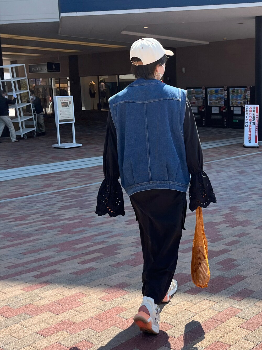 ブルー系のベスト、ブラック系のシャツ/ブラウス、オレンジ系のトートバッグを着用したレディースの春コーディネートの3枚目の写真