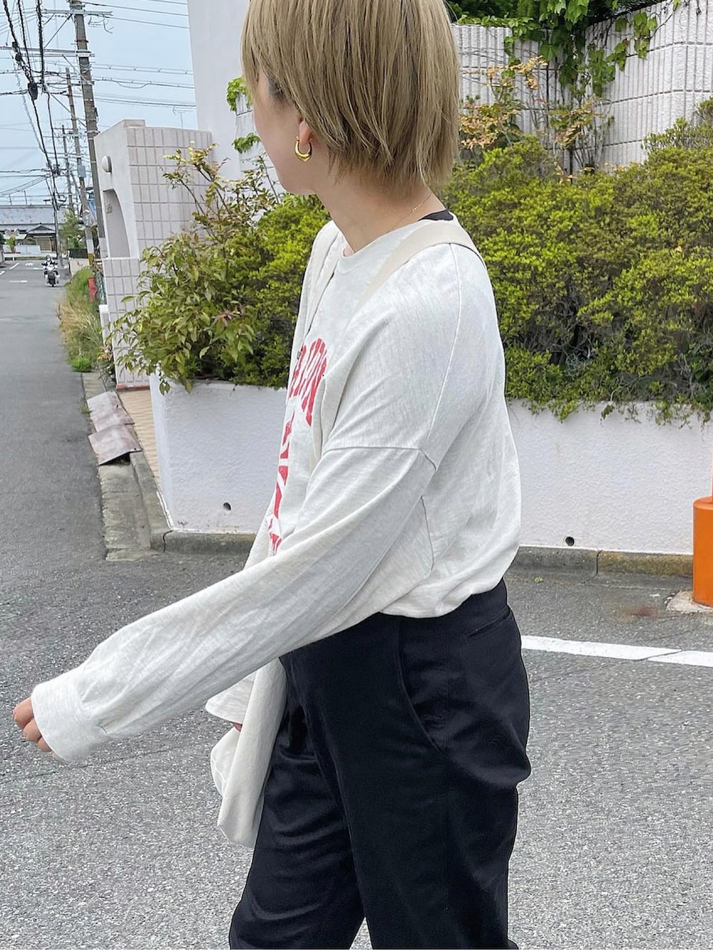 ホワイト系のショルダーバッグ、ブラック系のチノパンツ、ホワイト系のスニーカーを着用したレディースの夏コーディネートの3枚目の写真