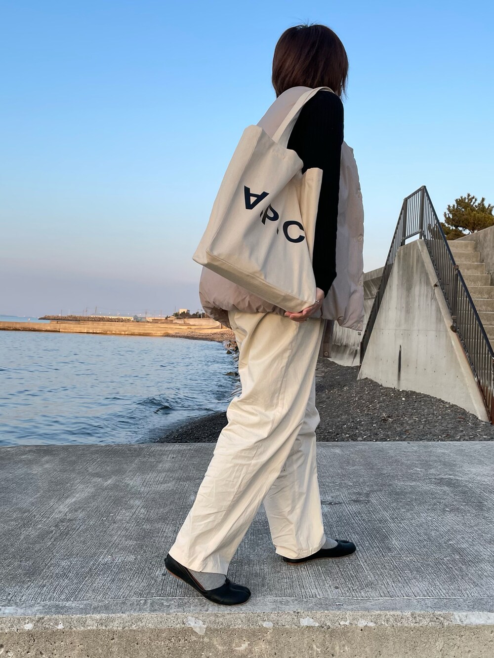 ホワイト系のその他パンツ、ベージュ系のダウンベスト、ブラック系のその他シューズを着用したレディースの春コーディネートの2枚目の写真