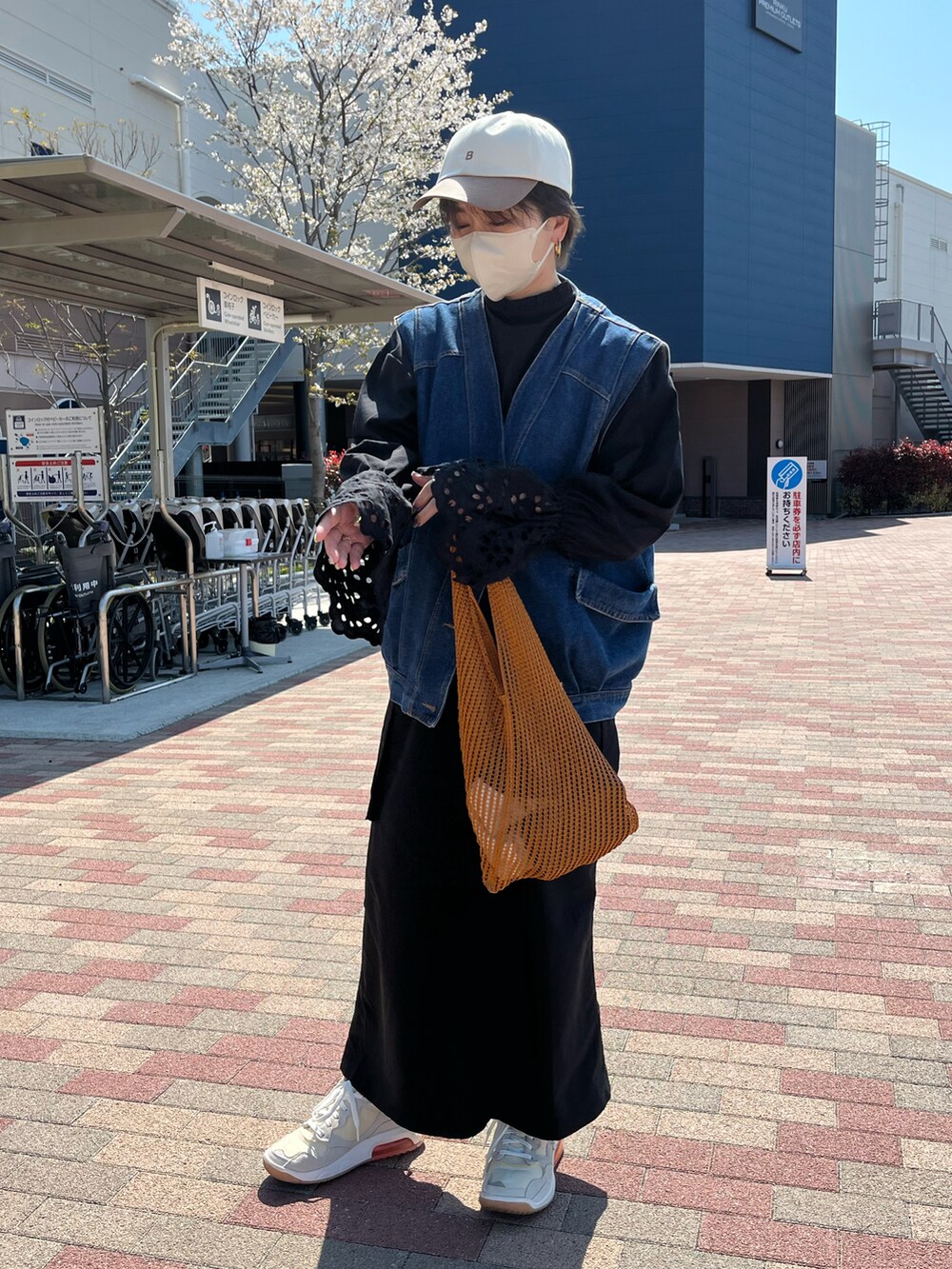 ブルー系のベスト、ブラック系のシャツ/ブラウス、オレンジ系のトートバッグを着用したレディースの春コーディネートの2枚目の写真