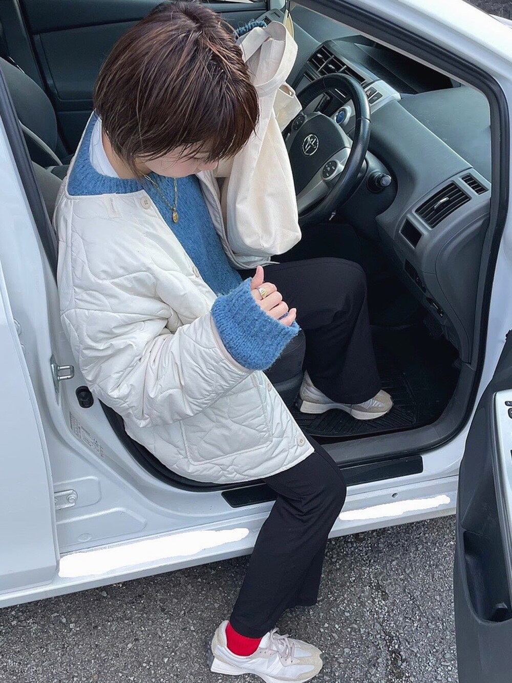 ホワイト系のトートバッグ、ブルー系のニット/セーター、ホワイト系のスニーカーを着用したレディースの春コーディネートの2枚目の写真