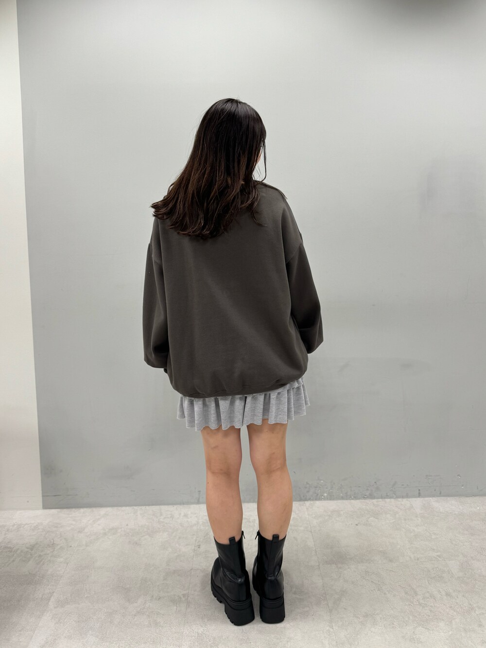ブラック系のTシャツ/カットソー、グレー系のスカート、ブラック系のブーツを着用したレディースの秋コーディネートの2枚目の写真