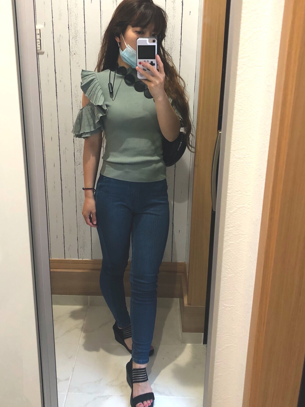 グリーン系のニット/セーター、ブルー系のデニムパンツ、ブラック系のサンダルを着用したレディースの夏コーディネートの2枚目の写真