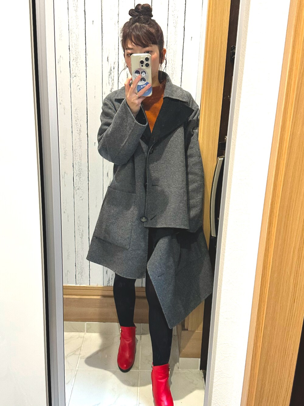 グレー系のダウンジャケット/コート、レッド系のブーツ、オレンジ系のニット/セーターを着用したレディースの秋コーディネートの2枚目の写真