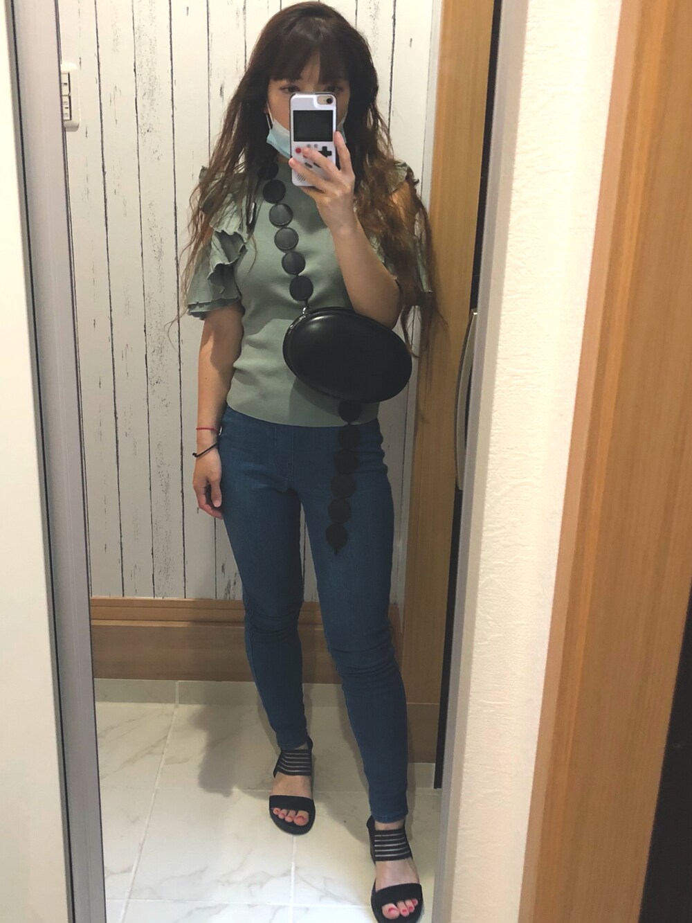 グリーン系のニット/セーター、ブルー系のデニムパンツ、ブラック系のサンダルを着用したレディースの夏コーディネートの3枚目の写真