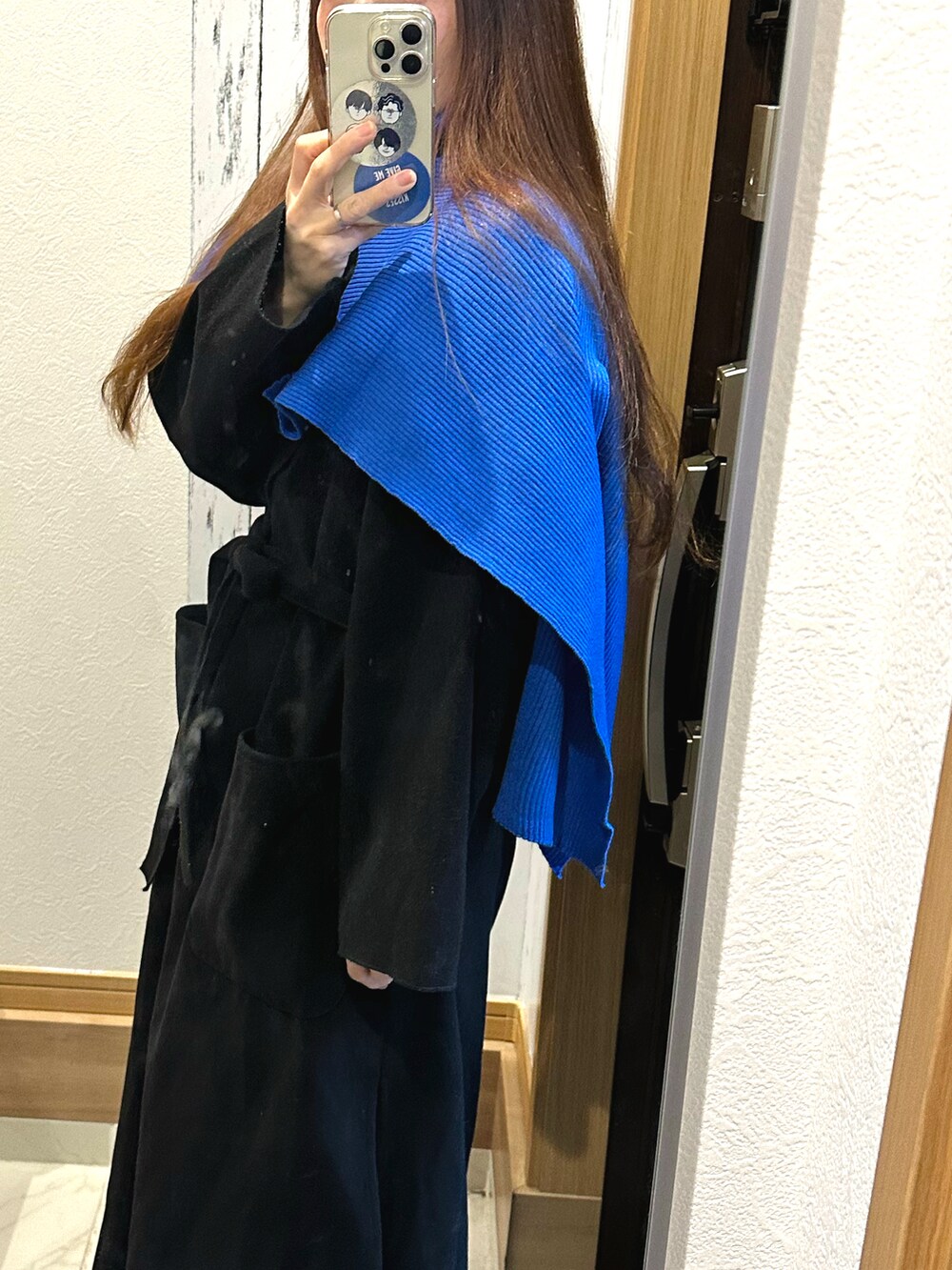 ブルー系のスカート、ブラック系のチェスターコート、ブラック系のニット/セーターを着用したレディースの冬コーディネートの3枚目の写真