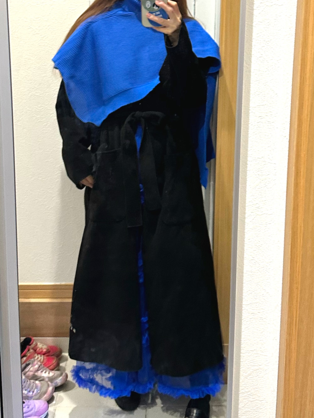 ブルー系のスカート、ブラック系のチェスターコート、ブラック系のニット/セーターを着用したレディースの冬コーディネートの2枚目の写真