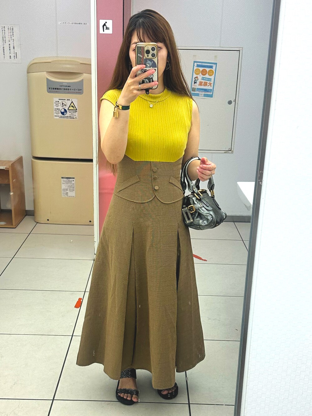 イエロー系のワンピース、シルバー系のハンドバッグ、グリーン系のアナログ腕時計を着用したレディースの秋コーディネートの2枚目の写真