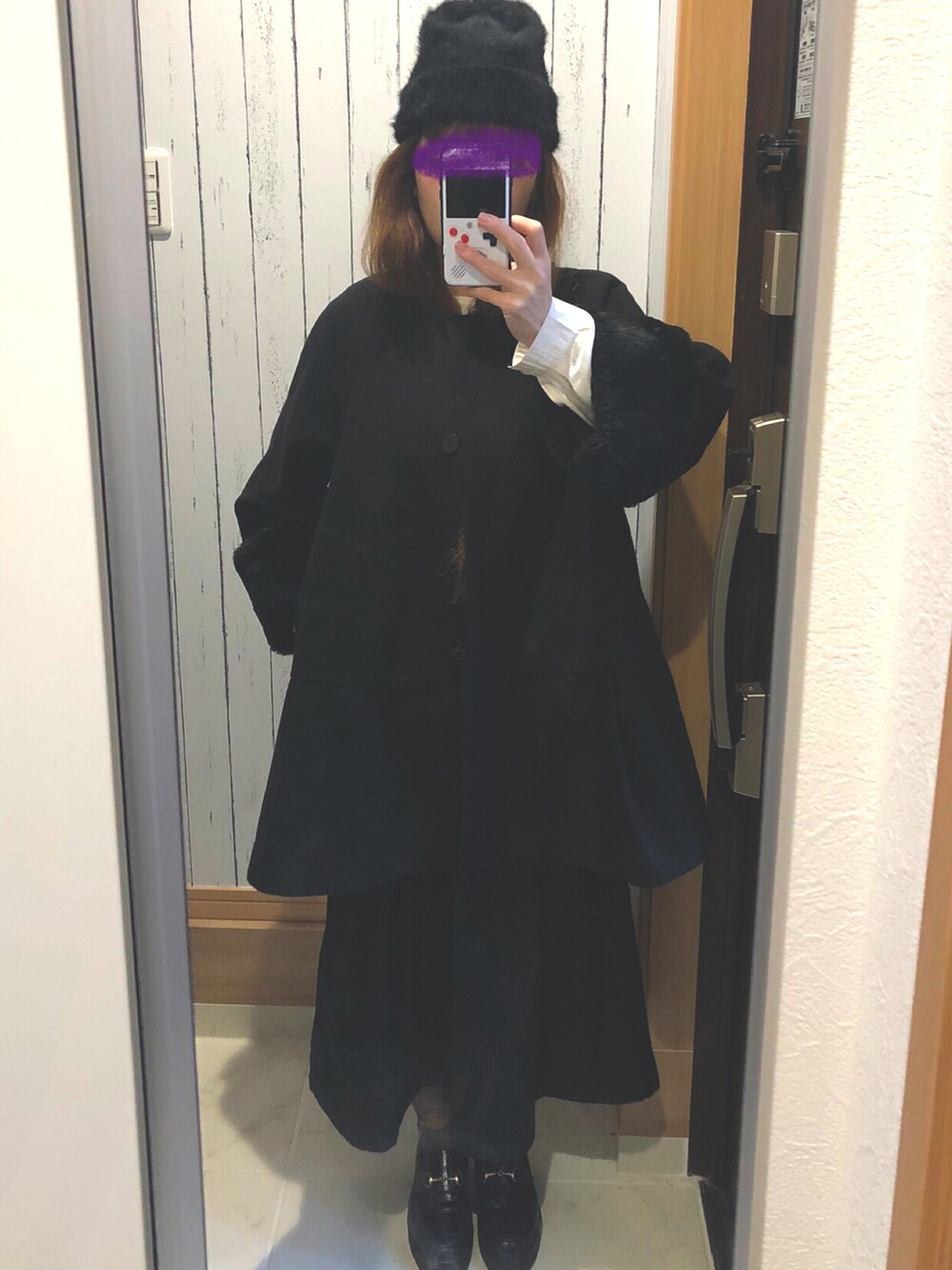 ブラック系のノーカラーコート、ブラック系のニットキャップ/ビーニーを着用したレディースの冬コーディネートの2枚目の写真