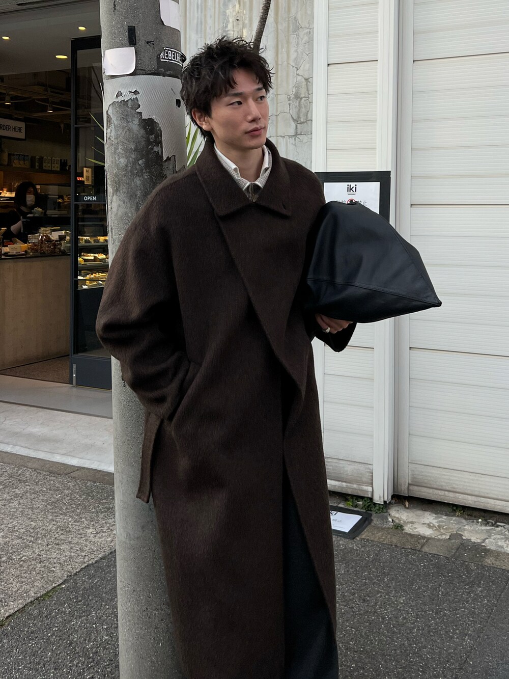 ブラウン系のチェスターコート、グレー系のチノパンツ、ブラック系のシューズを着用したメンズの冬コーディネートの2枚目の写真