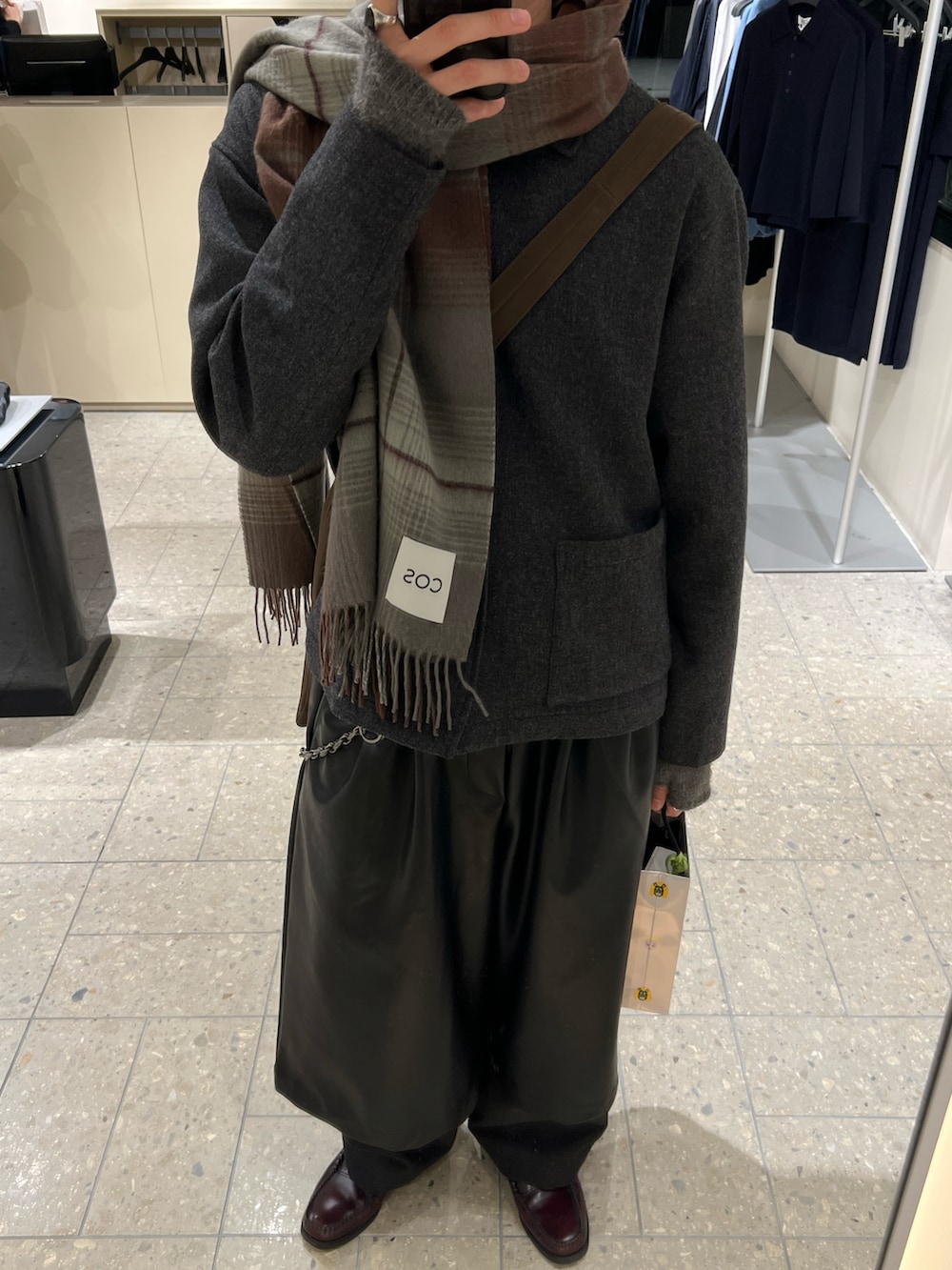 レッド系のローファー、ブラック系のその他パンツ、ブラウン系のショルダーバッグを着用したメンズの冬コーディネートの3枚目の写真