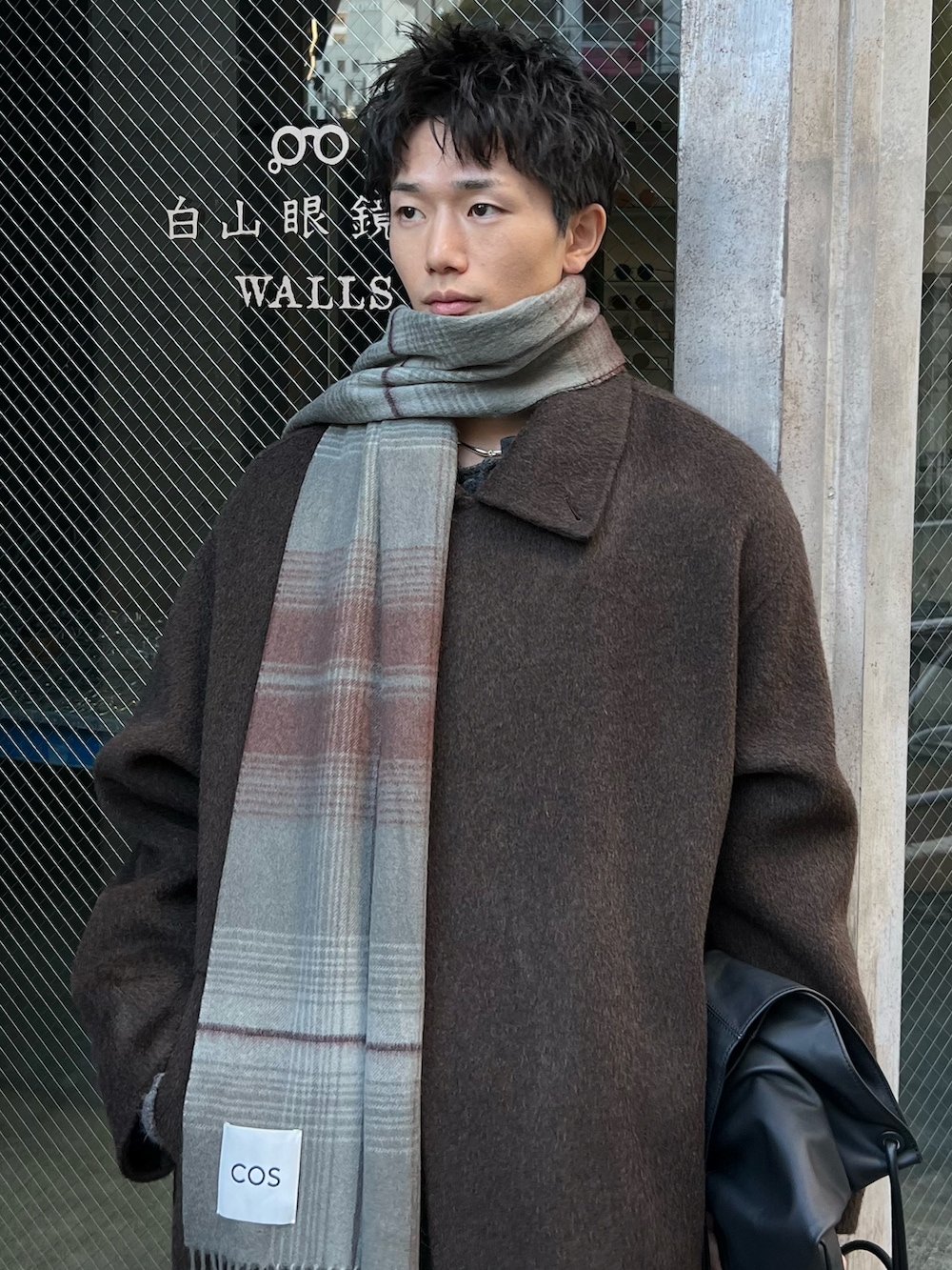 ブラウン系のスニーカー、ブルー系のデニムパンツ、ブラウン系のチェスターコートを着用したメンズの冬コーディネートの2枚目の写真