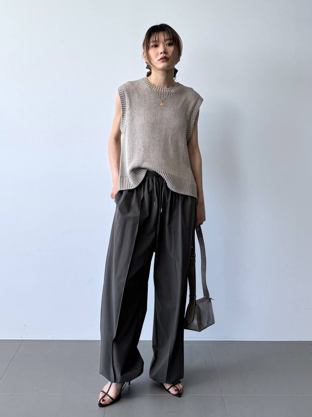 ブラック系のサンダル、グレー系のその他パンツ、ベージュ系のTシャツ/カットソーを着用したレディースの春コーディネートの2枚目の写真