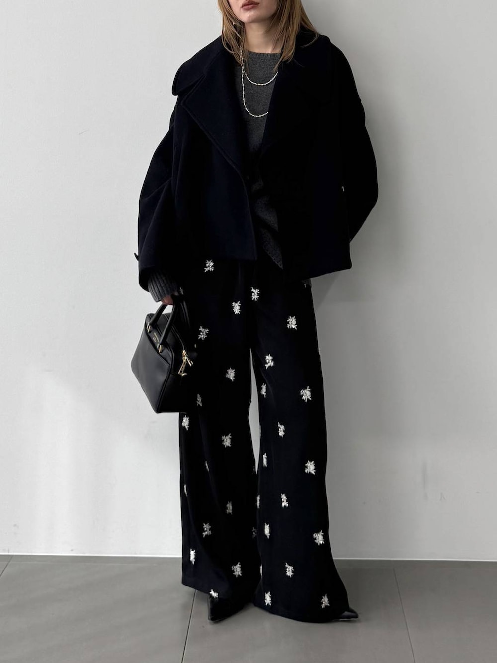 グレー系のニット/セーター、ブラック系のボストンバッグ、ブルー系のピーコートを着用したレディースの秋コーディネートの3枚目の写真