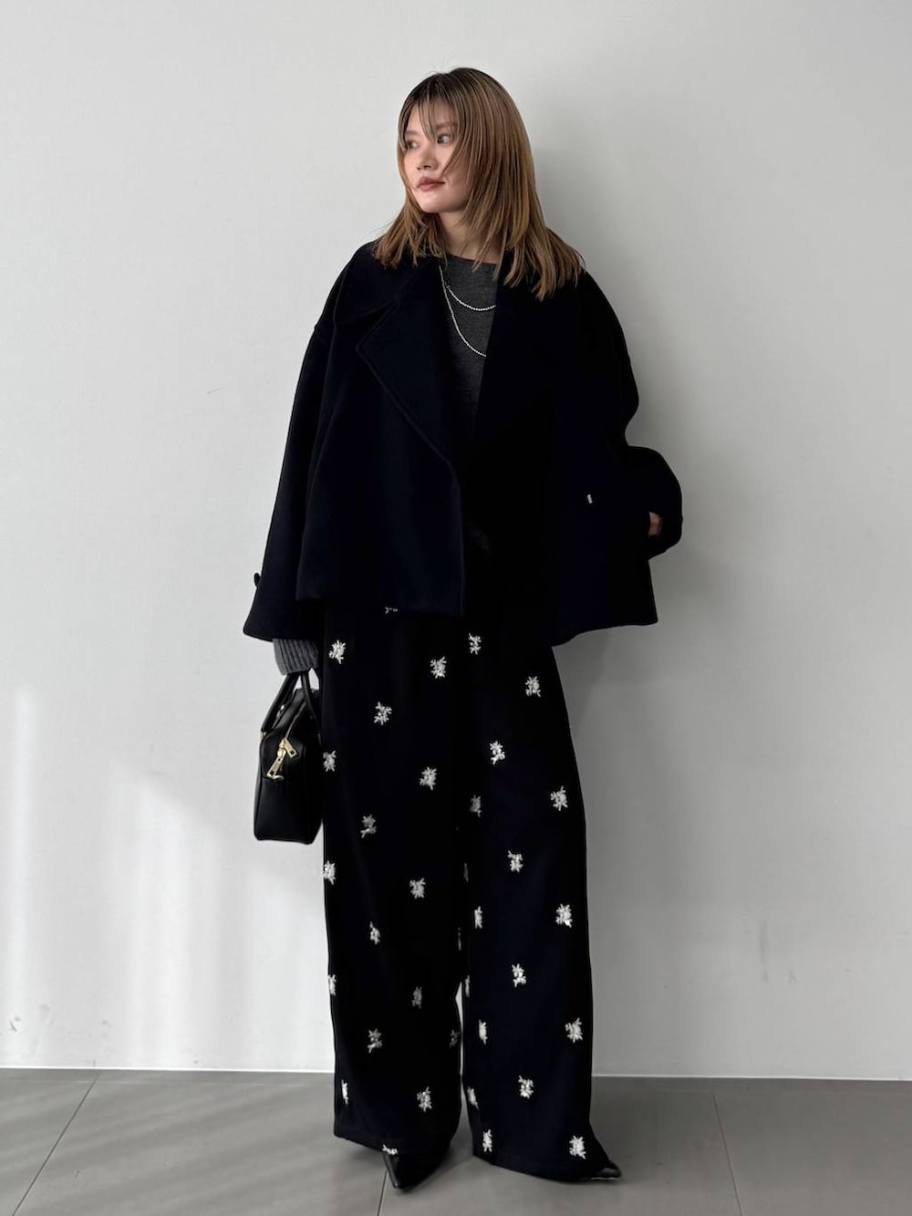 グレー系のニット/セーター、ブラック系のボストンバッグ、ブルー系のピーコートを着用したレディースの秋コーディネートの2枚目の写真