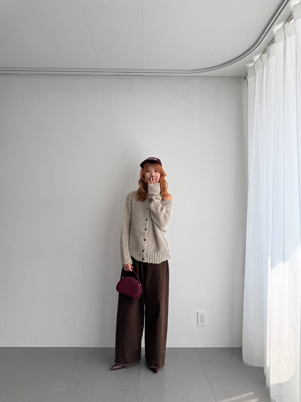 グリーン系のニット/セーター、レッド系のハンドバッグ、レッド系のブーツを着用したレディースの秋コーディネートの3枚目の写真