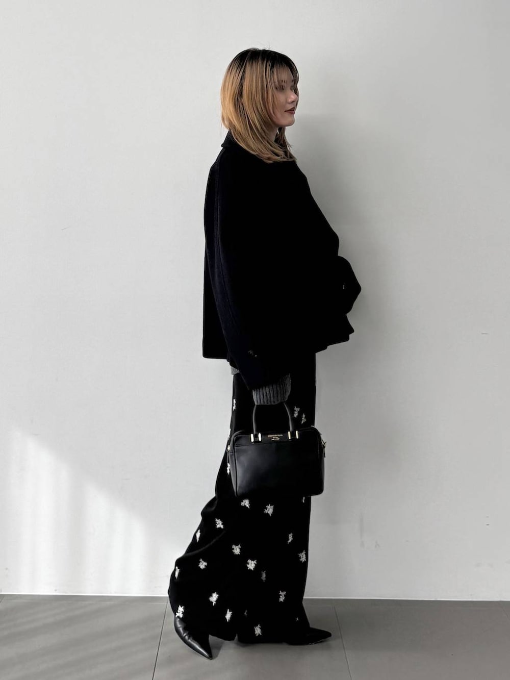 グレー系のニット/セーター、ブラック系のボストンバッグ、ブルー系のピーコートを着用したレディースの秋コーディネートの6枚目の写真