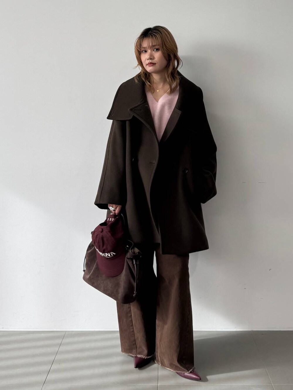 ピンク系のニット/セーター、レッド系のブーツ、ブラウン系のピーコートを着用したレディースの秋コーディネートの6枚目の写真