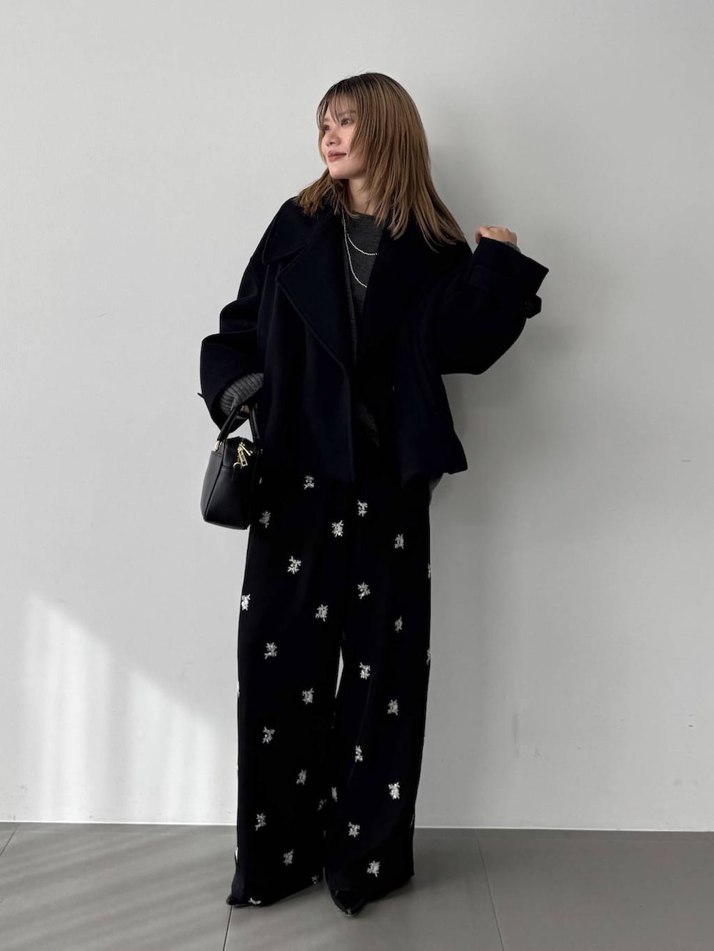 グレー系のニット/セーター、ブラック系のボストンバッグ、ブルー系のピーコートを着用したレディースの秋コーディネートの5枚目の写真