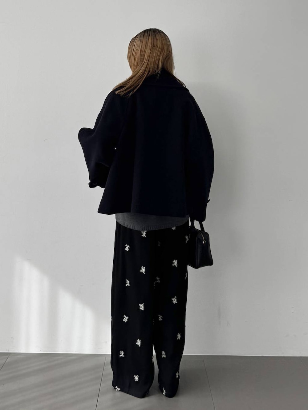 グレー系のニット/セーター、ブラック系のボストンバッグ、ブルー系のピーコートを着用したレディースの秋コーディネートの7枚目の写真