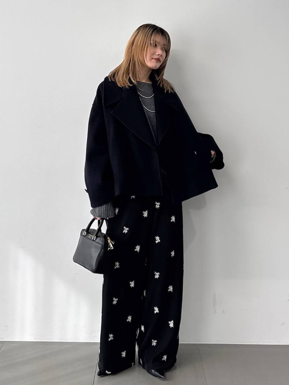 グレー系のニット/セーター、ブラック系のボストンバッグ、ブルー系のピーコートを着用したレディースの秋コーディネートの4枚目の写真