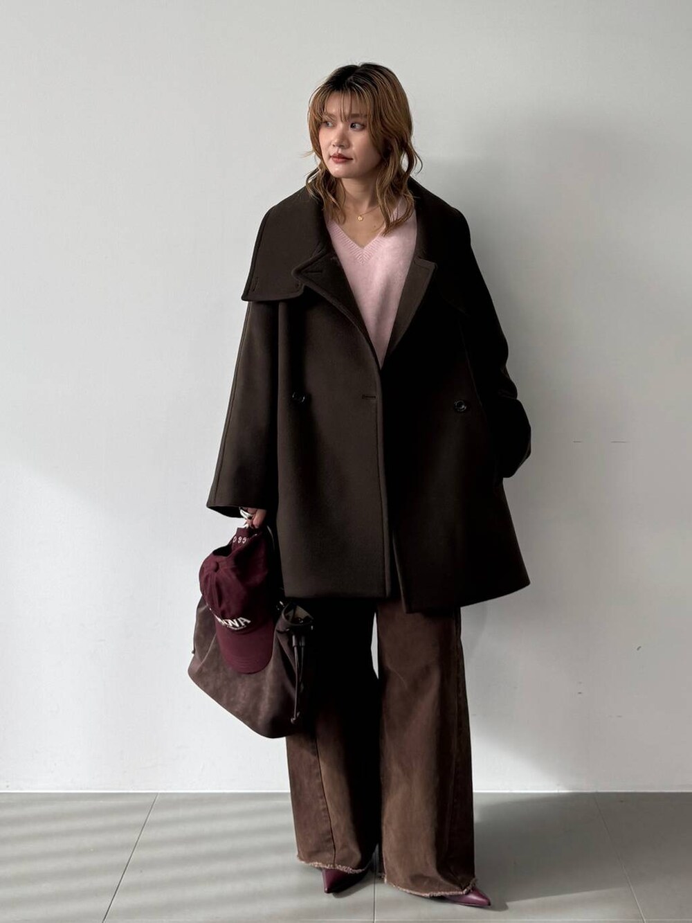 ピンク系のニット/セーター、レッド系のブーツ、ブラウン系のピーコートを着用したレディースの秋コーディネートの5枚目の写真