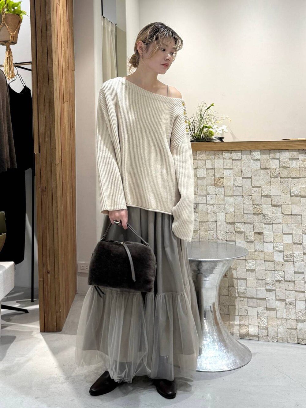 ブラウン系のハンドバッグ、ベージュ系のニット/セーター、ベージュ系のスカートを着用したレディースの冬コーディネートの3枚目の写真