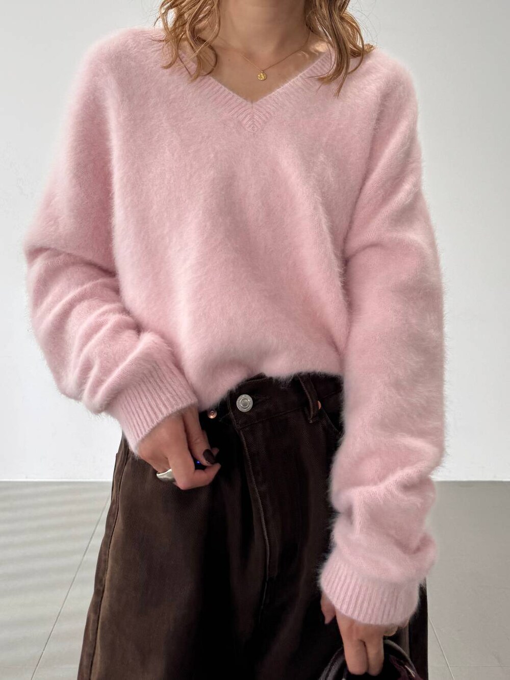 ピンク系のニット/セーター、レッド系のブーツ、ブラウン系のトートバッグを着用したレディースの秋コーディネートの9枚目の写真