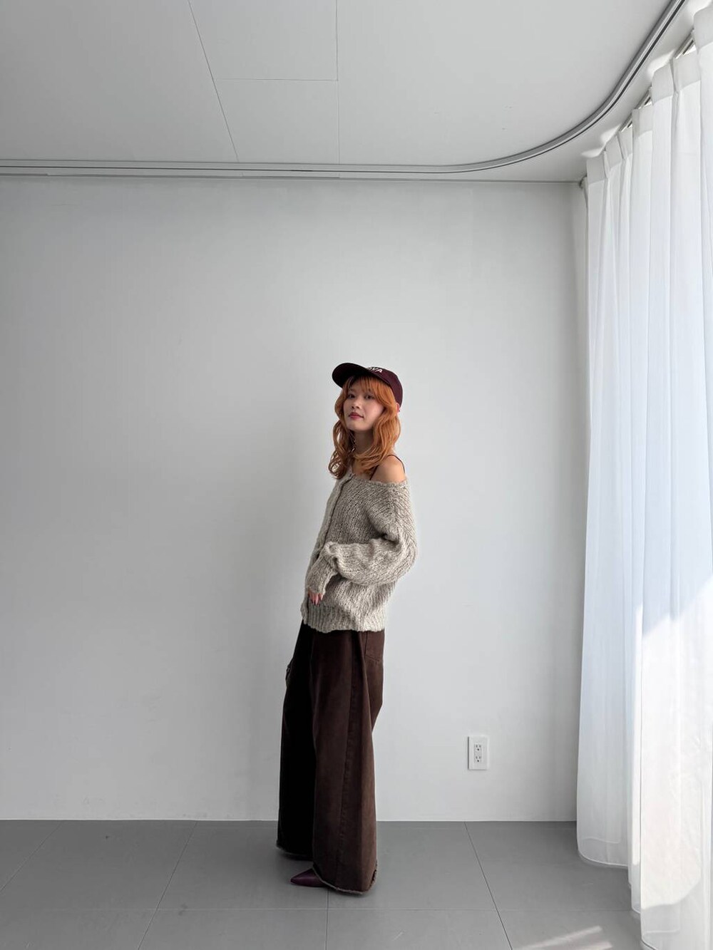 グリーン系のニット/セーター、レッド系のハンドバッグ、レッド系のブーツを着用したレディースの秋コーディネートの5枚目の写真