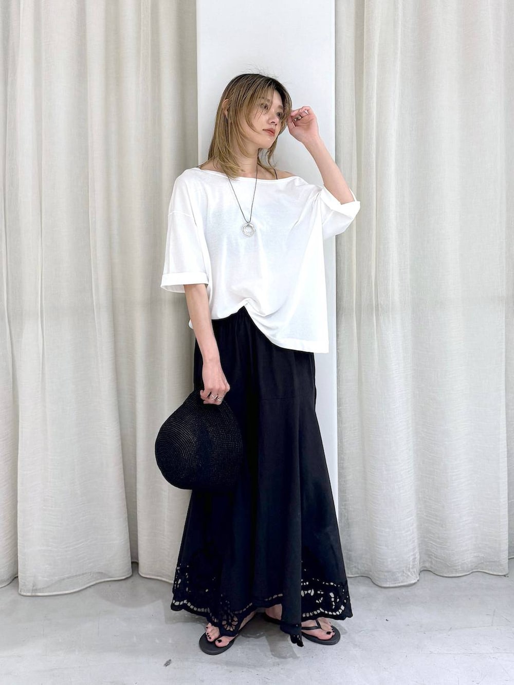 ブラック系のスカート、ブラック系のサンダル、ホワイト系のTシャツ/カットソーを着用したレディースの夏コーディネートの2枚目の写真