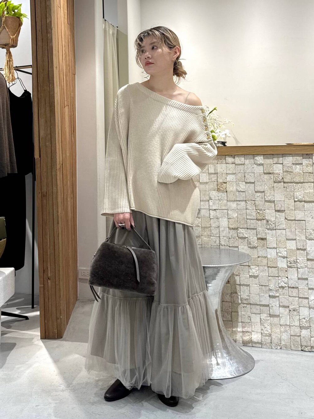 ブラウン系のハンドバッグ、ベージュ系のニット/セーター、ベージュ系のスカートを着用したレディースの冬コーディネートの2枚目の写真