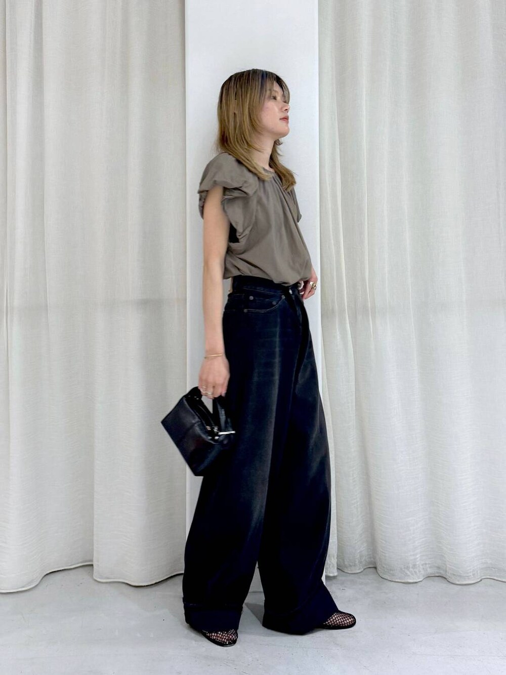 ブラック系のデニムパンツ、ベージュ系のシャツ/ブラウスを着用したレディースの夏コーディネートの4枚目の写真