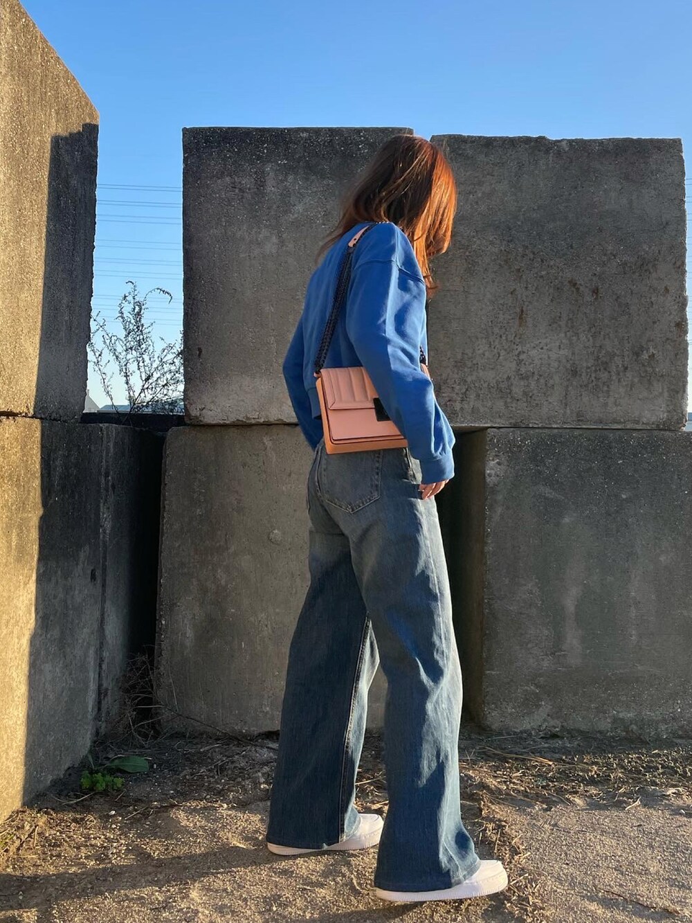 ブルー系のスウェット、ピンク系のショルダーバッグ、ホワイト系のスニーカーを着用したレディースの秋コーディネートの3枚目の写真