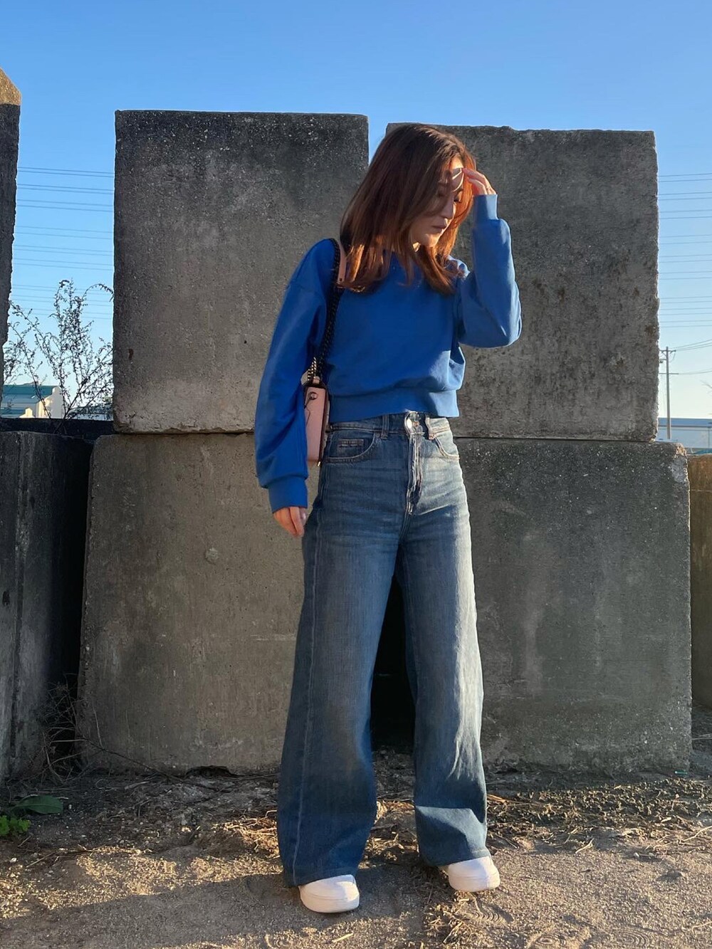 ブルー系のスウェット、ピンク系のショルダーバッグ、ホワイト系のスニーカーを着用したレディースの秋コーディネートの4枚目の写真