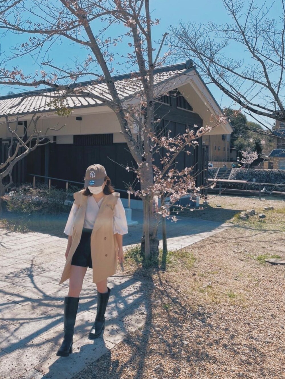 ホワイト系のショルダーバッグ、ベージュ系のトレンチコート、ブラック系のブーツを着用したレディースの秋コーディネートの4枚目の写真