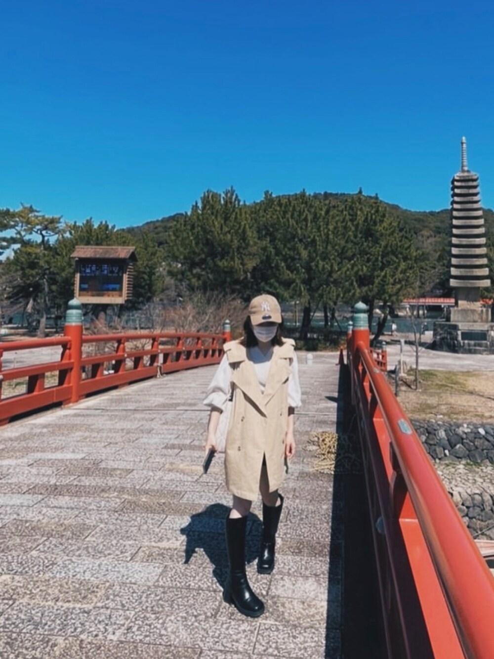 ホワイト系のショルダーバッグ、ベージュ系のトレンチコート、ブラック系のブーツを着用したレディースの秋コーディネートの3枚目の写真