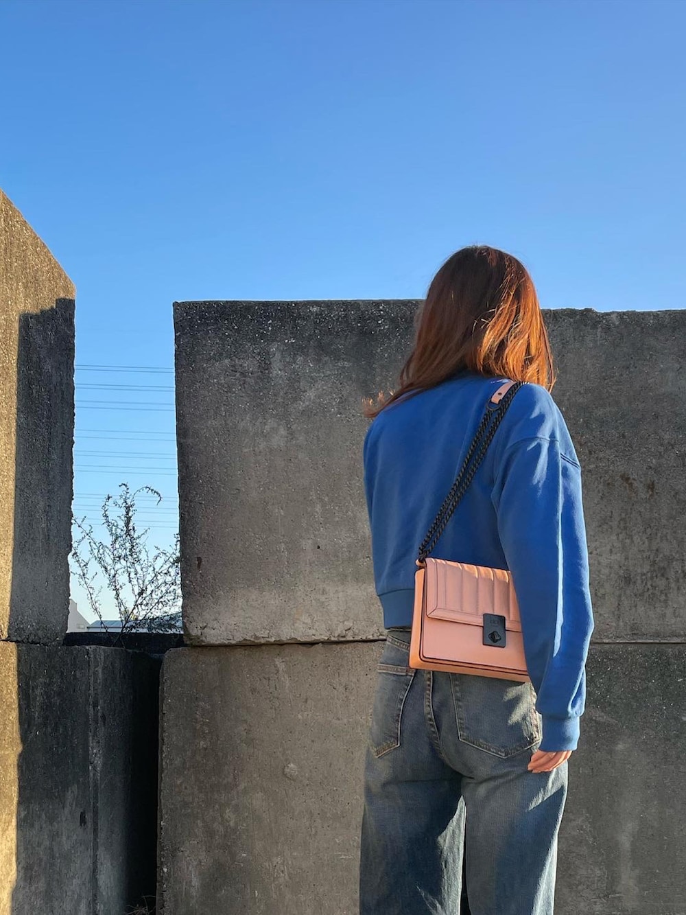 ブルー系のスウェット、ピンク系のショルダーバッグ、ホワイト系のスニーカーを着用したレディースの秋コーディネートの2枚目の写真