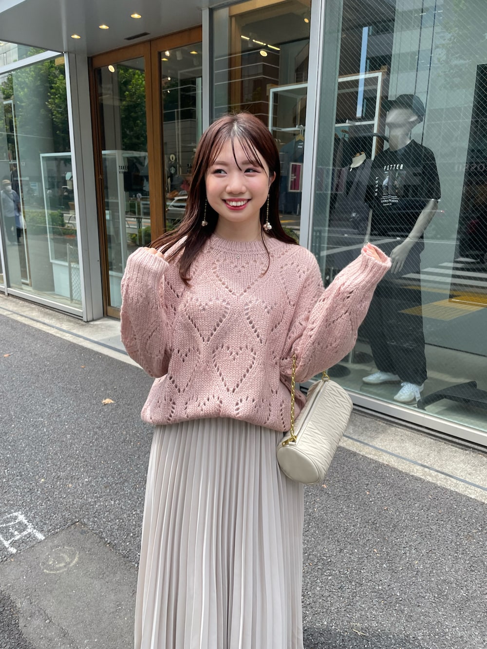 ピンク系のニット/セーター、ベージュ系のスカートを着用したレディースの夏コーディネートの3枚目の写真